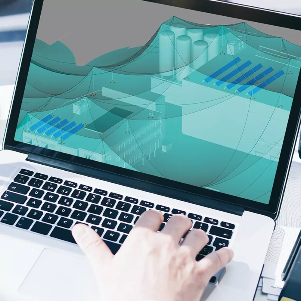 Laptop screen showing electrical planning software with a 3D protection zone model while a person works at the keyboard.