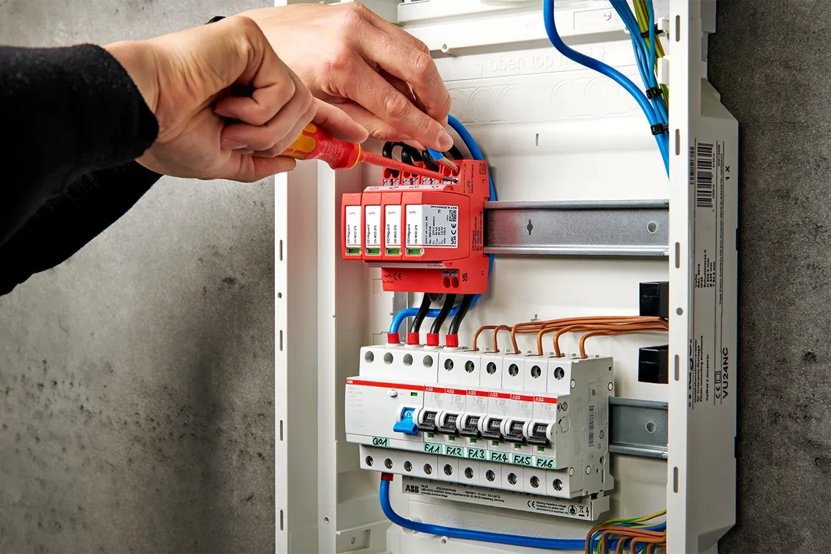 Electrician installs surge protection in a fuse box.